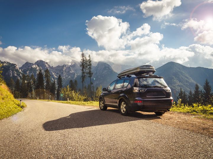 Car pulled to the side of a mountain road with a storage pod on top.