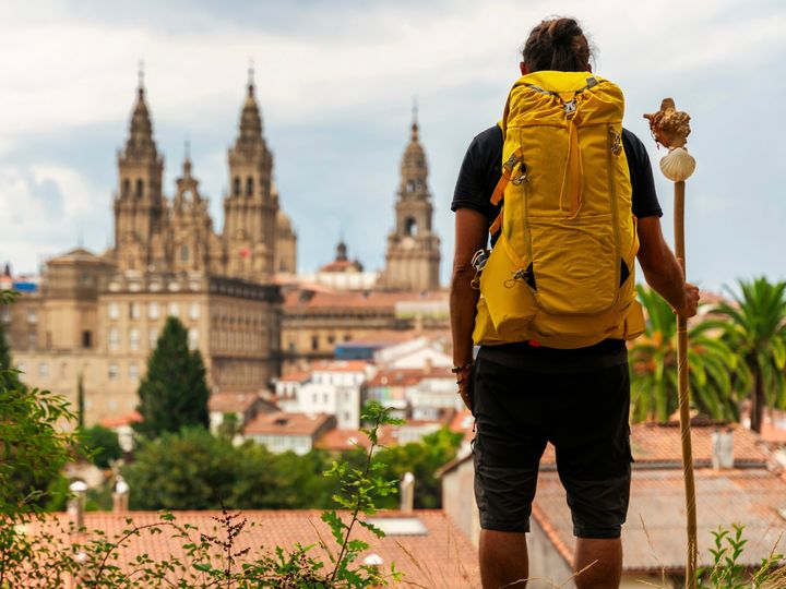 A pilgrim looking at the Cathedral of Santiago de Compostela in Spaink, backpack on his back. 