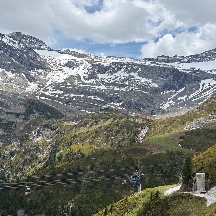 A view of Hintertux Glacier in Austria with snow-capped mountains on top and greenery down below.