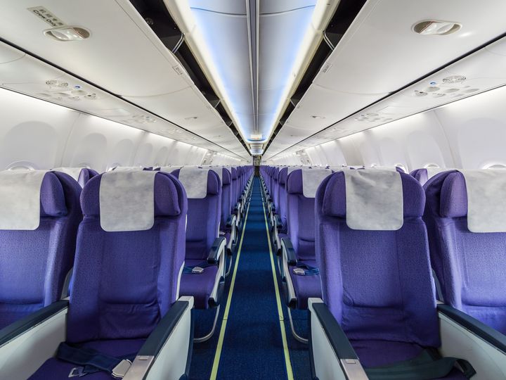 Rows of purple airplane seats in an empty plane cabin.