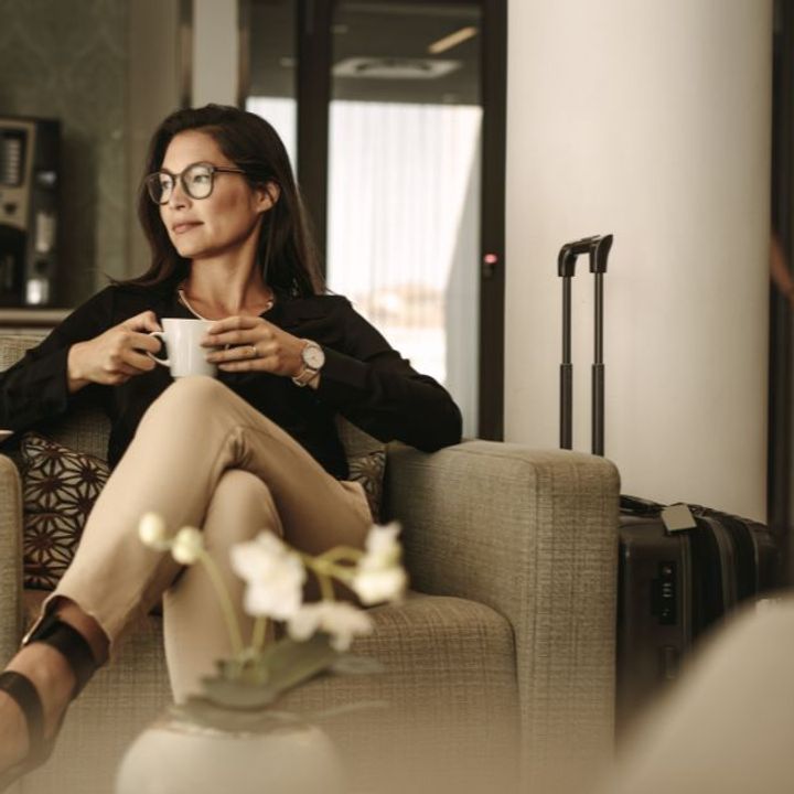 A woman sits in an airport lounge while holding a cup of coffee.