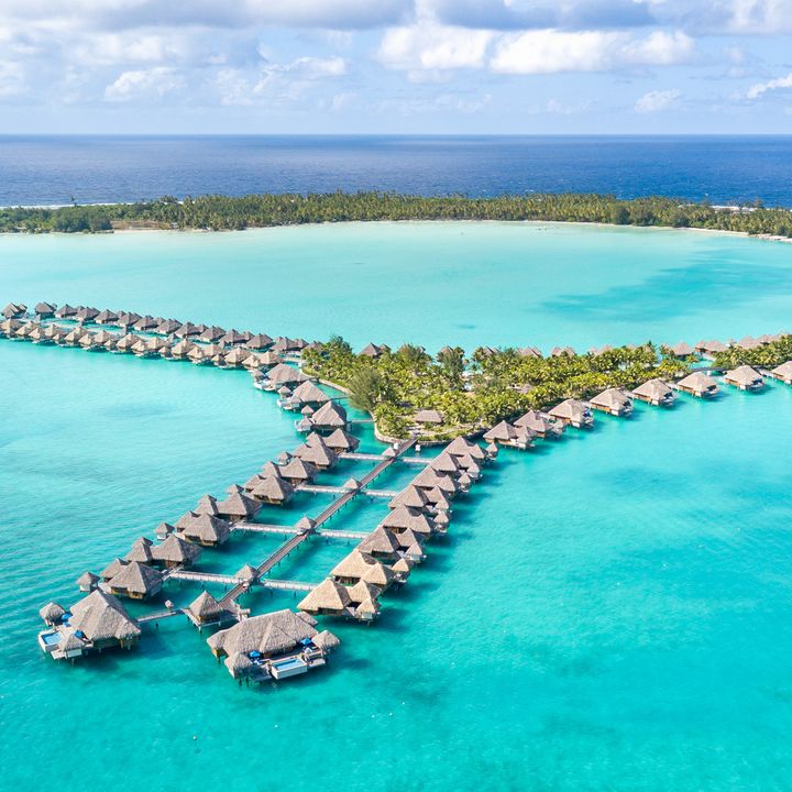 Rows of overwater villas atop bright blue water at The St. Regis, Bora Bora.