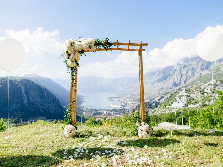 An arch decorated for a wedding with a scenic view on a mountain for a destination wedding.