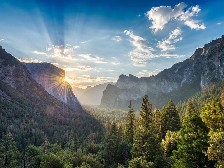 A sunrise peeks through rock cliffs at the tunnel view vista point at Yosemite National Park.