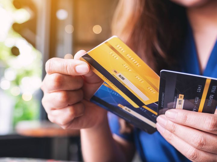 A hand is seen holding three credit cards fanned out.