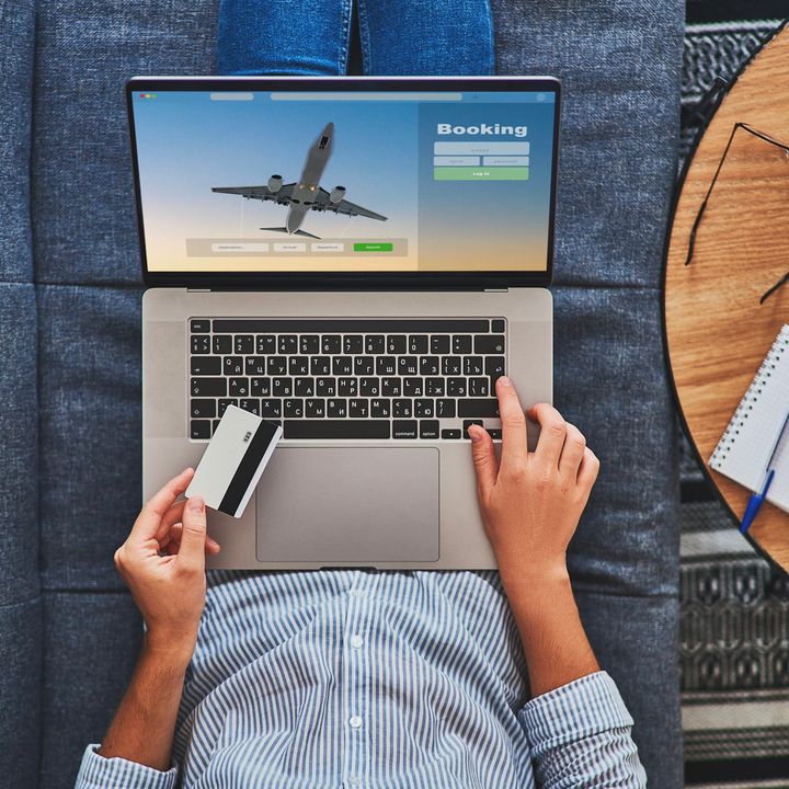 Overhead shot of someone buying plane tickets using a computer and credit card.