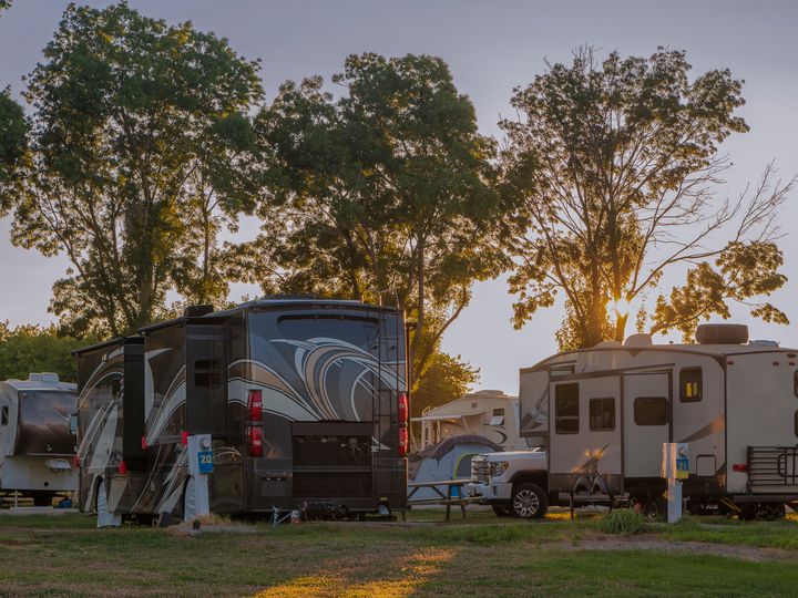 A bunch of RVs parked for camping at a resort at sunset.