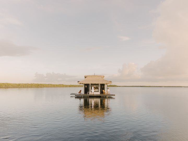 A floating thatched-roof bungalow floating on top of the water in the Florida Keys.
