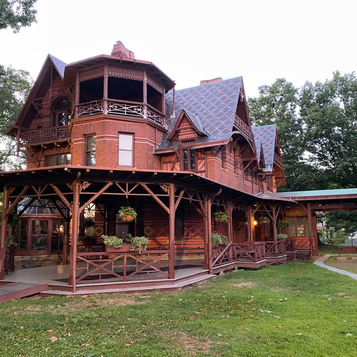 The red brick exterior of the Mark Twain House & Museum with a wraparound porch and arched Victorian-style roof.