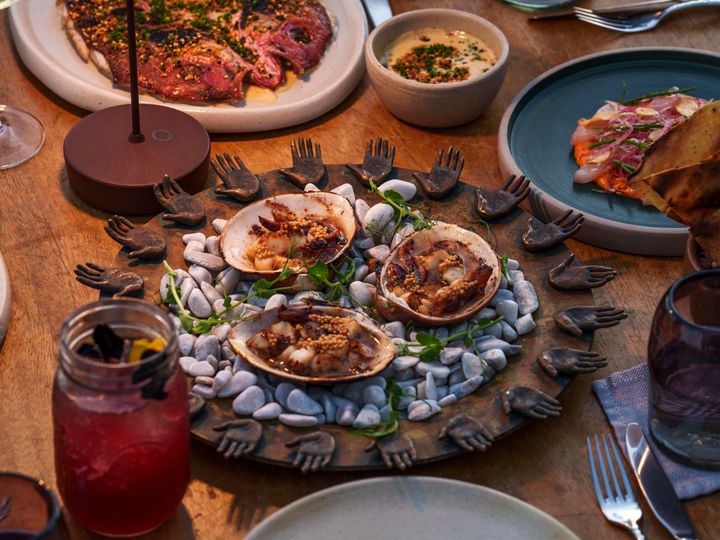 An overhead shot of a table filled with glasses and dishes of food with a circular dish in the middle.