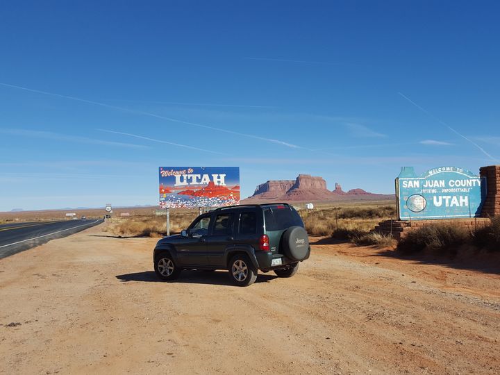 A car on the side of the road next to a welcome to utah sign.
