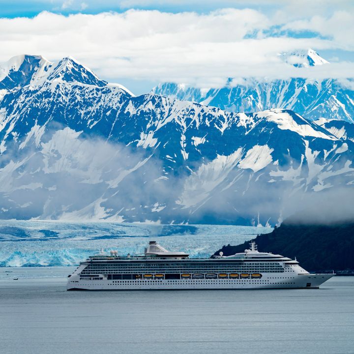 A cruise ship in Alaska passing glaciers and snow-capped mountains.