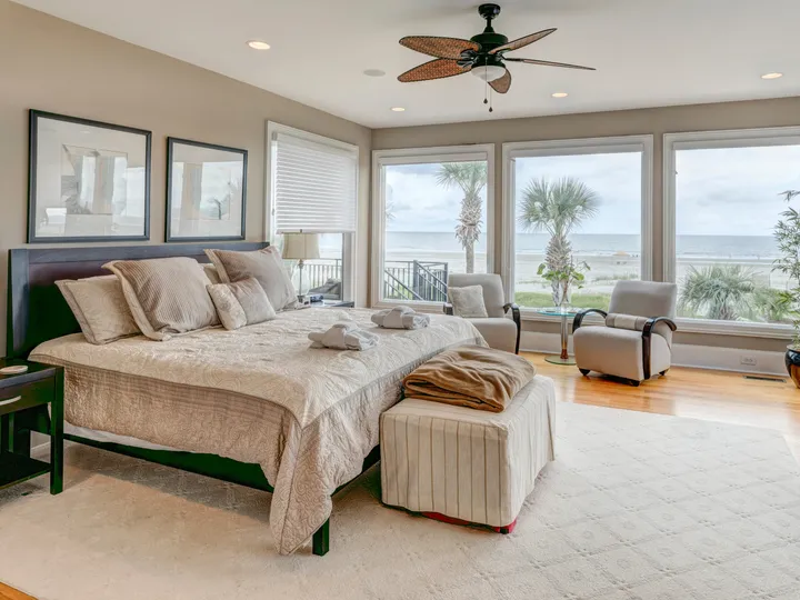 A beautifully designed bedroom with a well-made bed and large windows overlooking a tropical landscape.