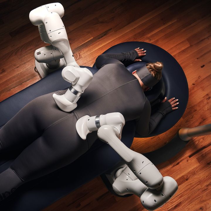A woman is face down on a massage bed receiving a massage from the Aescape machine.