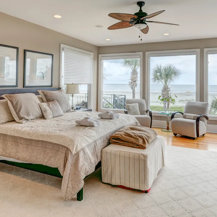 A beautifully designed bedroom with a well-made bed and large windows overlooking a tropical landscape.