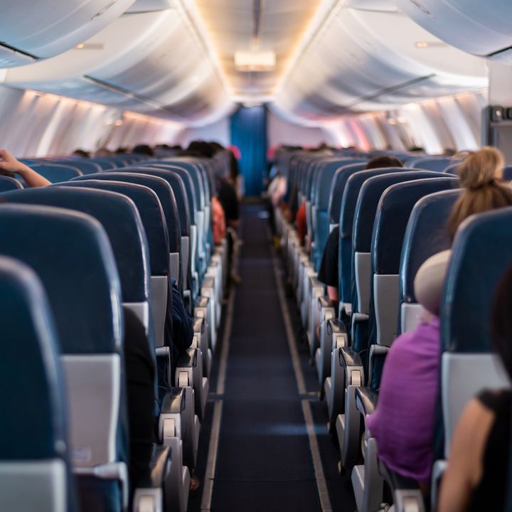 Rows of seats in an economy plane cabin as seen from behind.