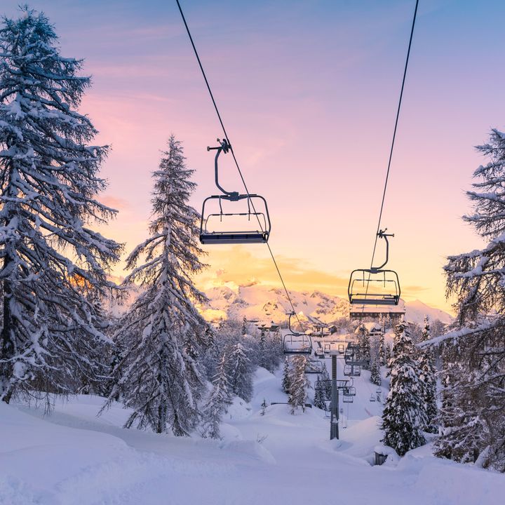 A chairlift is visible over a snowy mountain at sunset in winter.
