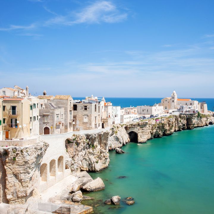 The town of Vieste in the Puglia region of Italy with a rock barrier extending into the sea topped with white buildings.