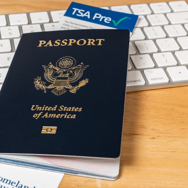 United States of America Passport with Department of Homeland Security TSA Pre Check registration information card. US Passport on desk with computer keyboard.