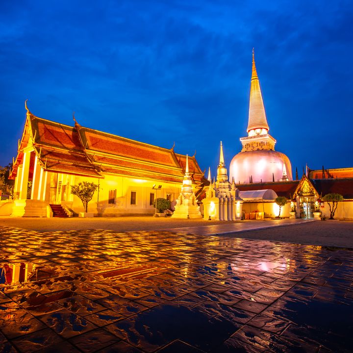 The monastery buildings of Wat Phra Mahathat Woramahawihan with cloudy sky at night at Nakhon Si Thammarat in Thailand. 