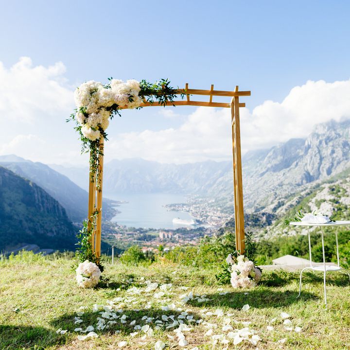 An arch decorated for a wedding with a scenic view on a mountain for a destination wedding.
