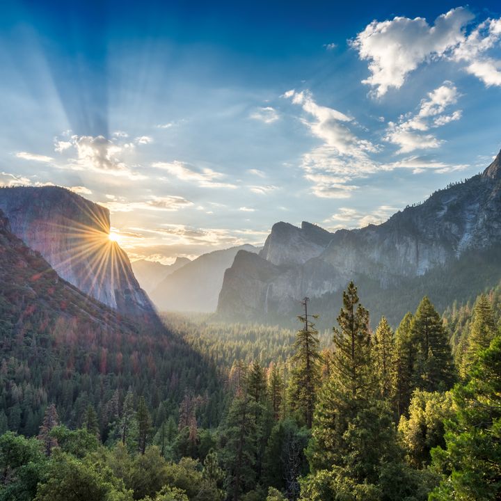 A sunrise peeks through rock cliffs at the tunnel view vista point at Yosemite National Park.