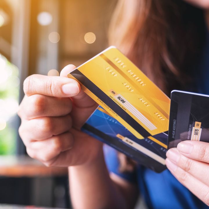 A hand is seen holding three credit cards fanned out.